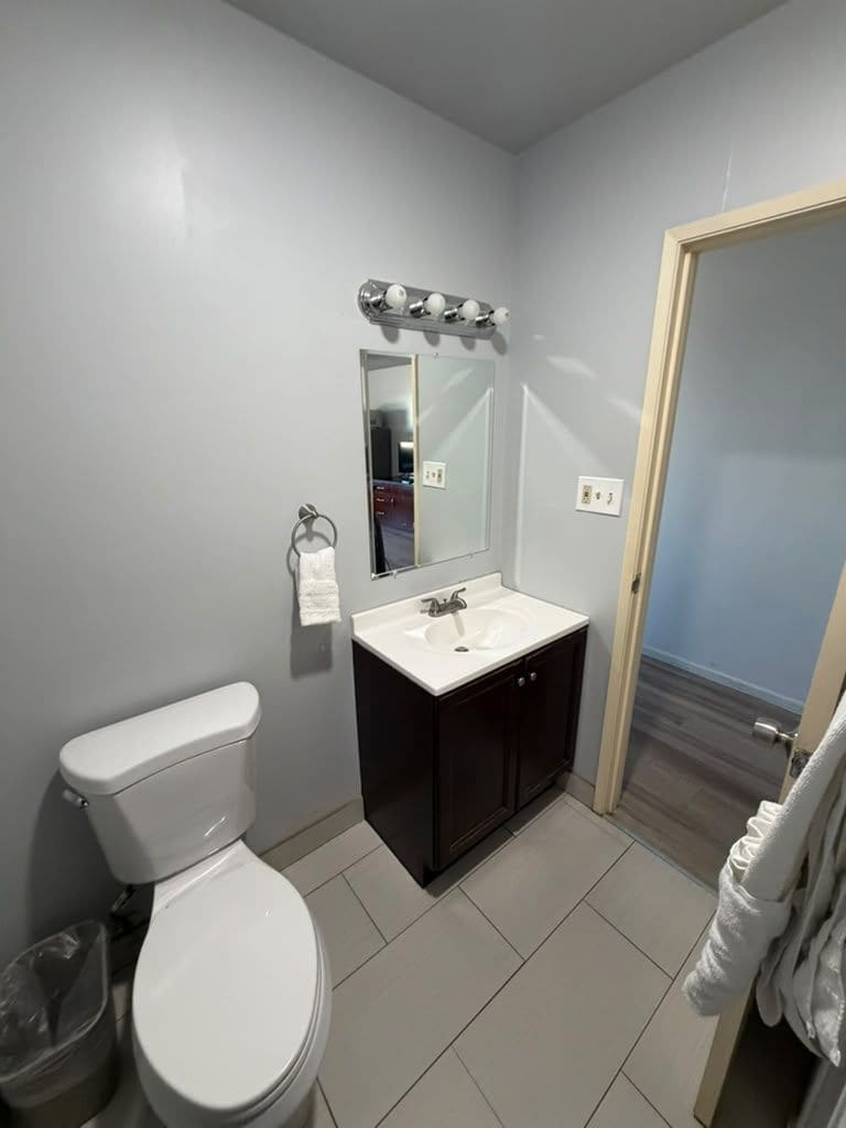 A small bathroom with a toilet, sink, and mirror.