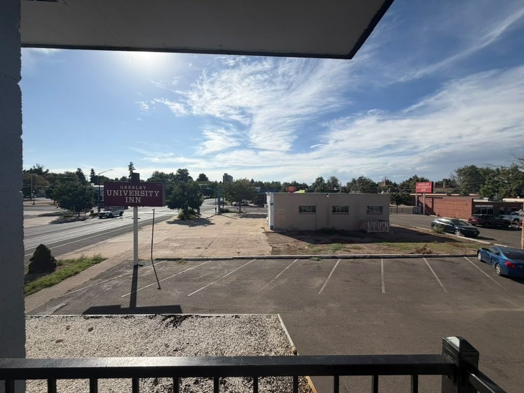 A parking lot with a sign for O'REILLY UNIVERSITY INN and a building in the background.