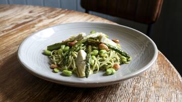 A plate of pasta with asparagus and nuts on a wooden table.