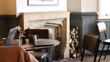 Un comedor acogedor con chimenea, muebles de madera y una computadora portátil sobre una mesa.