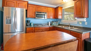 A kitchen with wooden cabinets, stainless steel appliances, and a granite countertop. - Flirty Flamingo, Too! 1 BDR 1BTH, with Shared in-ground pool! (Gulfport)