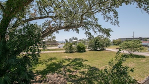 A grassy area with trees and a building in the background. - Flirty Flamingo, Too! 1 BDR 1BTH, with Shared in-ground pool! (Gulfport)