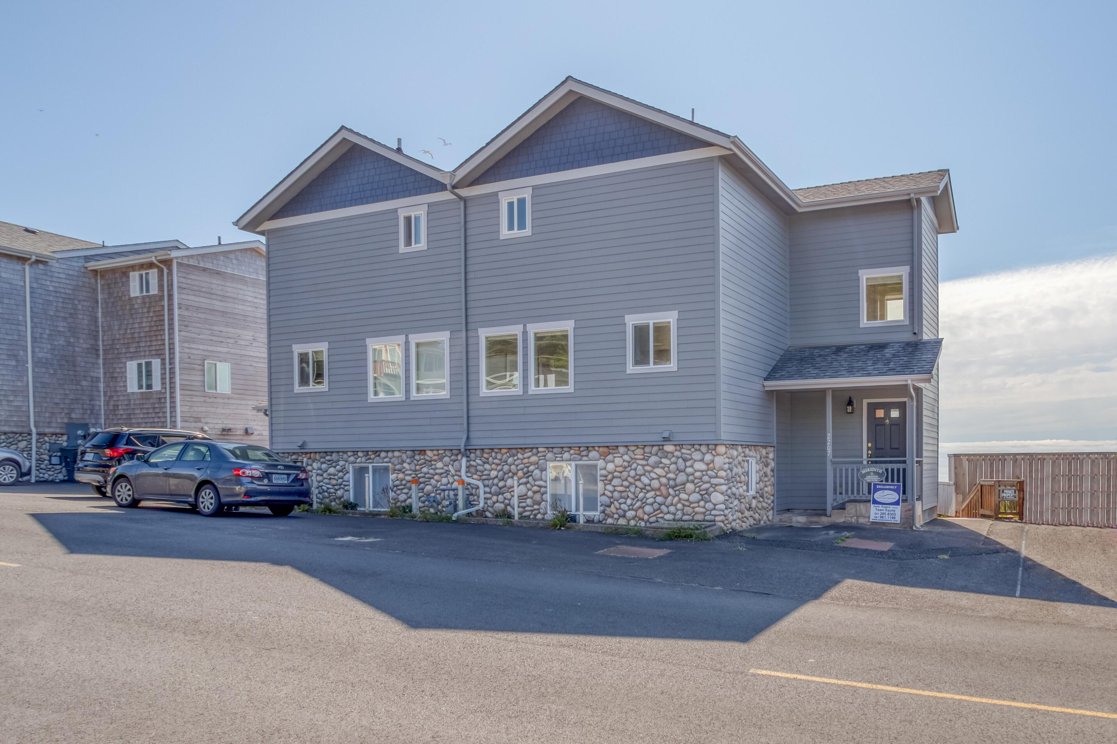 A multi-story residential building with a stone foundation and a grey exterior.