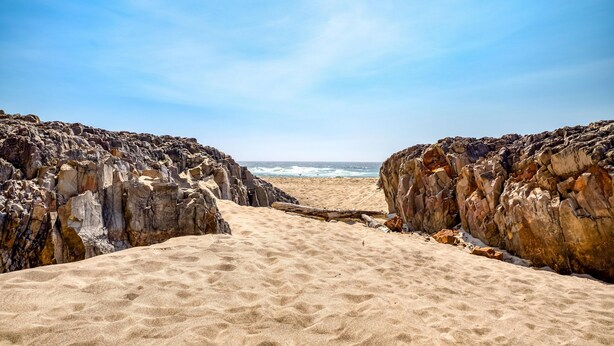A beach with rocky cliffs and a sandy path leading to the ocean. - Whale Watch Beach House (Lincoln City)