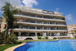 Un hôtel à plusieurs étages doté de balcons, d’une piscine et d’un jardin aménagé.