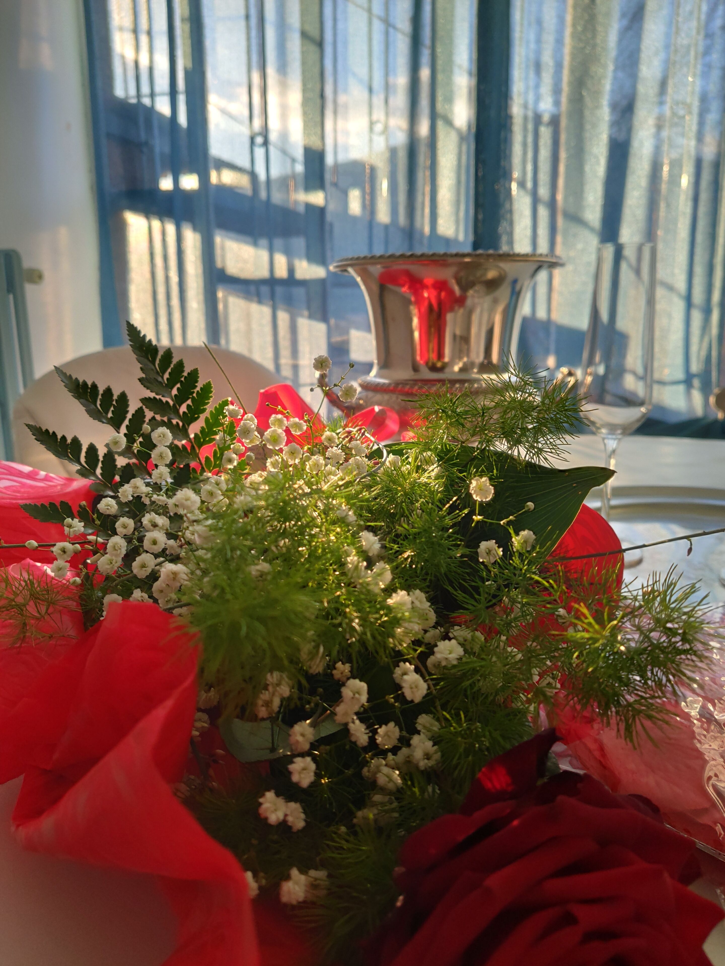A table with a floral arrangement, a silver candle holder, and a glass.