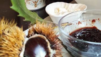 Ein Esstisch mit einer Schale Kastanien, einer Marmeladenschale und einer Tasse Tee.