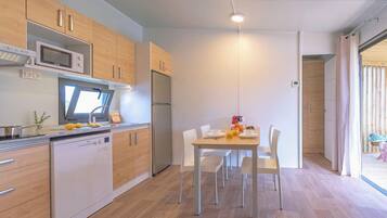 A modern kitchen with wooden cabinets, a built-in microwave, and a dining area with a table and chairs.