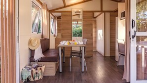 A cozy interior with a wooden ceiling, a dining area with a table and chairs, a bench, and a window with curtains. - Rubina Resort (Castello d'Empuries)