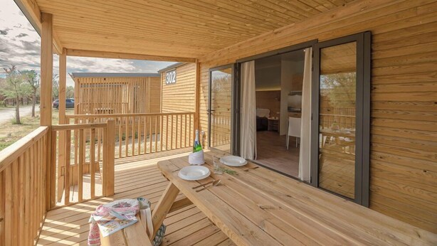 A wooden deck with a table set for two, a bottle of champagne, and a pair of glasses. - Rubina Resort (Castello d'Empuries)
