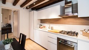 A modern kitchen with white cabinets, a stainless steel range hood, and a gas stove.