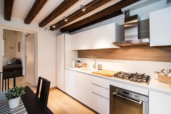 A modern kitchen with white cabinets, a stainless steel range hood, and a gas stove.