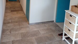 A hallway with a tiled floor, a blue door, and a white wall with a hat and mirror. - Villa under the pines, for 8 or 12 people (adjoining annex in summer) (Six-Fours-les-Plages)