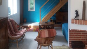 A living room with a blue wall, a wooden staircase, wicker chairs, and a fireplace. - Villa under the pines, for 8 or 12 people (adjoining annex in summer) (Six-Fours-les-Plages)