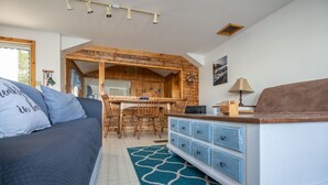 Un salon chaleureux avec un canapé, une table basse et un coin repas en bois.
