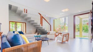 Un salon moderne avec un escalier, un canapé, une table basse et un fauteuil.