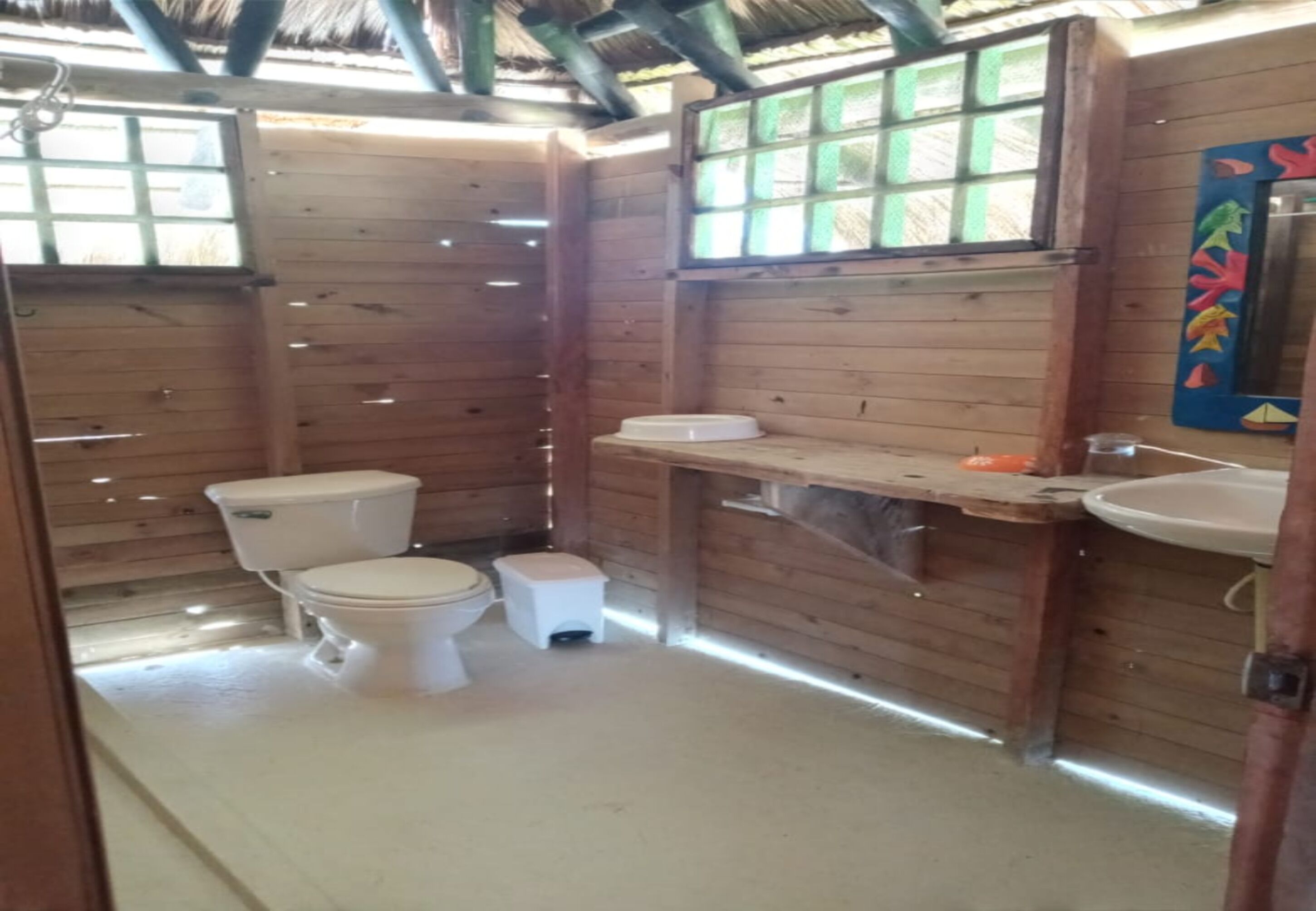 Un baño rústico con cabaña, que incluye inodoro, lavamanos y una ventana pequeña.