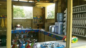 A rustic kitchen with wooden walls, a colorful backsplash, and shelves with dishes and jars. - Baru Punta Blanca (Cartagena)