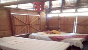 A rustic wooden room with two beds, each with a white bedspread and colorful pillows. - Baru Punta Blanca (Cartagena)