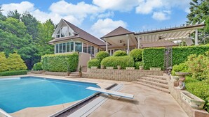 A swimming pool with a sunken seating area, a covered patio, and a landscaped garden with a stone wall and potted plants. - Private House Retreat on Beautiful Lake Hartwell with Private Pool (Hartwell)