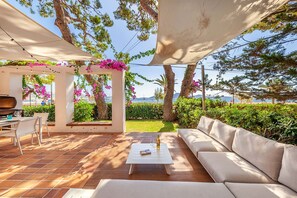 An outdoor patio with a white table, a sofa, and a grill.