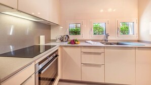 Eine moderne Küche mit Backofen, Spüle und einer Arbeitsplatte mit Wasserkocher und frischem Gemüse.