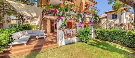 Een moderne villa met een ruime buitenzitplaats, een overdekt terras en een weelderige tuin.