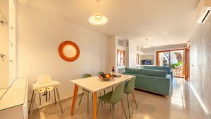 Ein modernes Wohnzimmer mit Essbereich, grünen Stühlen, einem weißen Tisch und einem grünen Sofa.