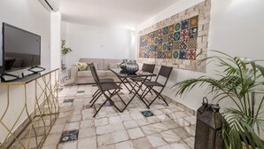 Ein Wohnzimmer mit Fernseher, einer Couch, einem Couchtisch und einer Wand mit Muster.