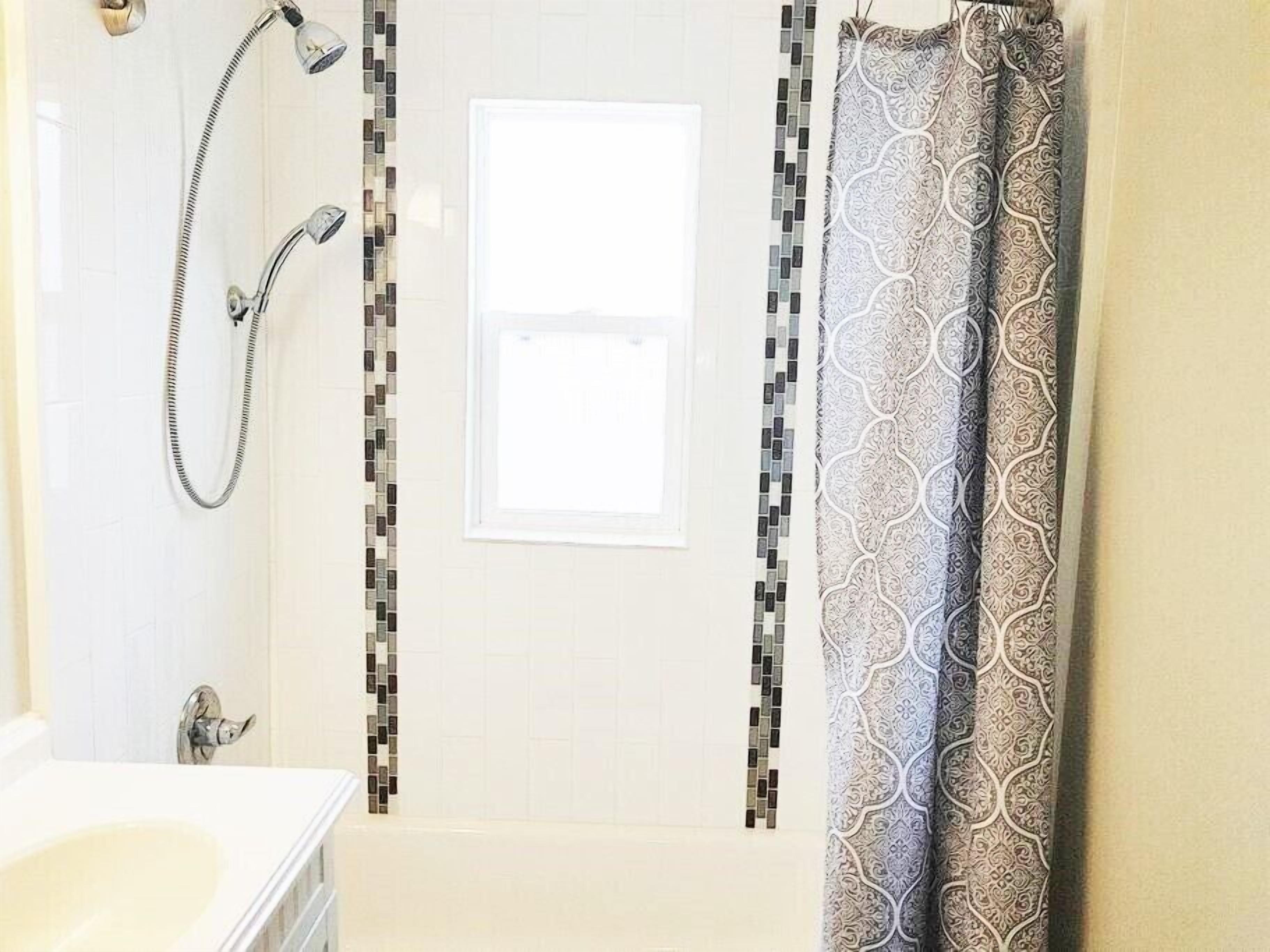 Modern main floor bathroom with tub and full shower.  Newly renovated with modern decor, fixtures and linens.