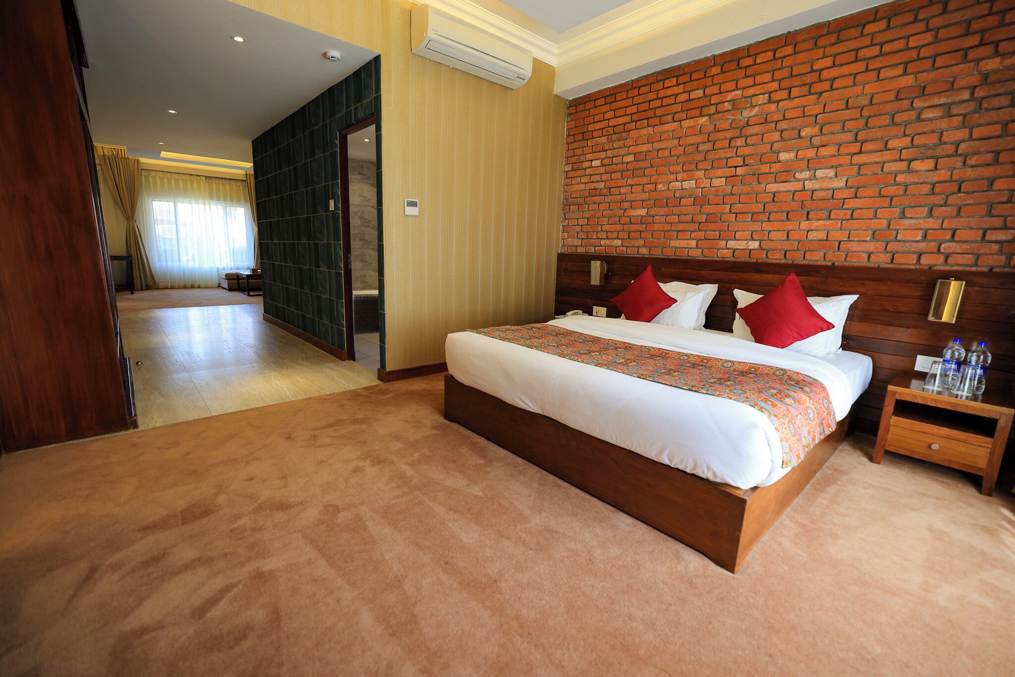 A hotel room with a large bed, a brick wall, and a wooden headboard.
