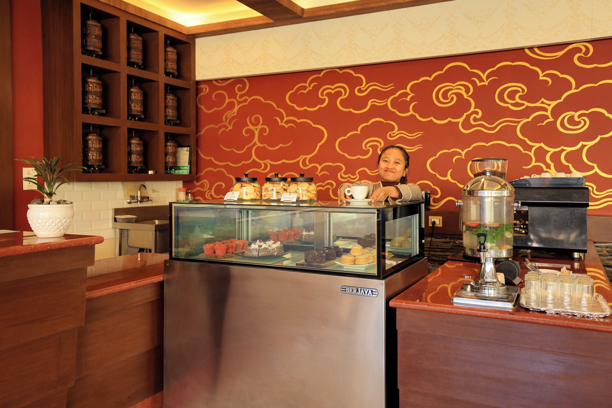 A coffee station with a display case, a coffee machine, and a tea station.