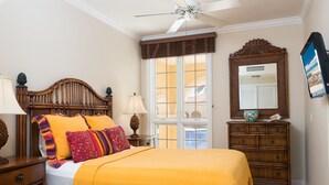 Ein Schlafzimmer mit einem Bett, einem Schminktisch, einem Spiegel und einem Deckenventilator.
