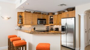 Eine moderne Küche mit Holzschränken, Edelstahlgeräten und einer Arbeitsplatte aus Granit.