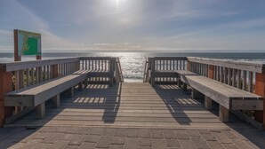 A wooden pier with benches leading to the ocean, a signboard, and a clear view of the sea. - Wandering Star (Depoe Bay)