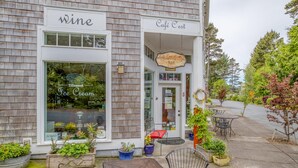 A storefront with a wine sign and a café sign. There are outdoor seating areas with tables and chairs. - Wandering Star (Depoe Bay)