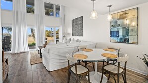 Ein geräumiges Zimmer mit großem Esstisch, heller Möbel und Blick ins Freie.