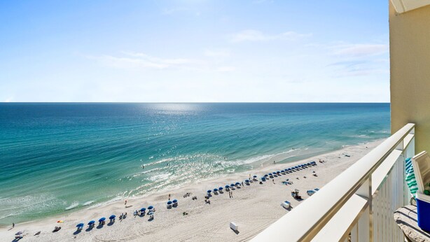 A beach view from a balcony with a clear sky, ocean, and beach umbrellas. - Emerald Beach by Book That Condo (Panama City Beach)