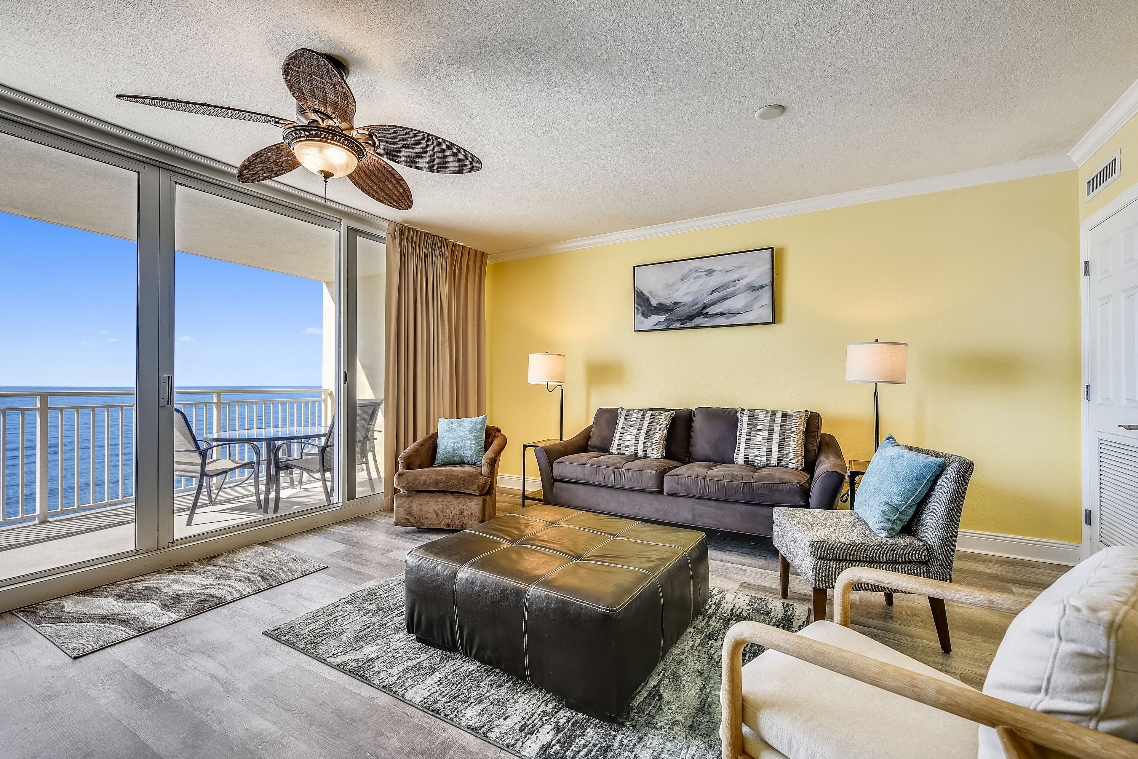 A living room with a balcony, a ceiling fan, a sofa, and a coffee table.