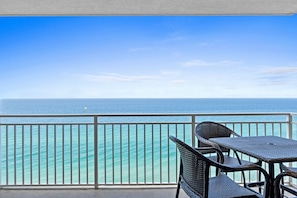 Enjoy the ocean view from this balcony with a table and two chairs.