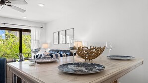 A modern dining area with a wooden table, two plates, two wine glasses, and a decorative bowl. - Beachwalk by Book That Condo (Panama City Beach)