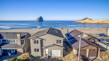 A coastal residential area with houses, a beach, and a rocky outcrop in the distance.