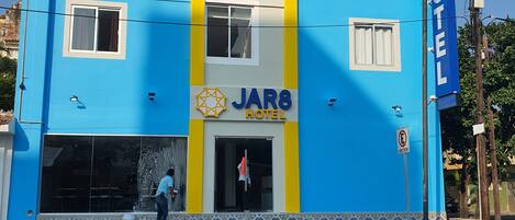 A JARS Hotel building with a blue facade, yellow vertical stripes, and a signboard.