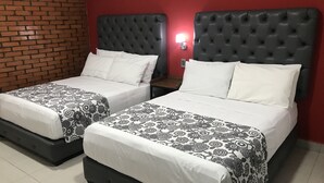 Two twin beds with black headboards and white bedding, a brick wall, and a red wall with a wall-mounted light. - Hotel Jar8 (Veracruz)