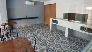 A modern kitchen with a built-in stove, a microwave, and a small refrigerator. There is a dining area with a wooden table and chairs. - Hotel Jar8 (Veracruz)