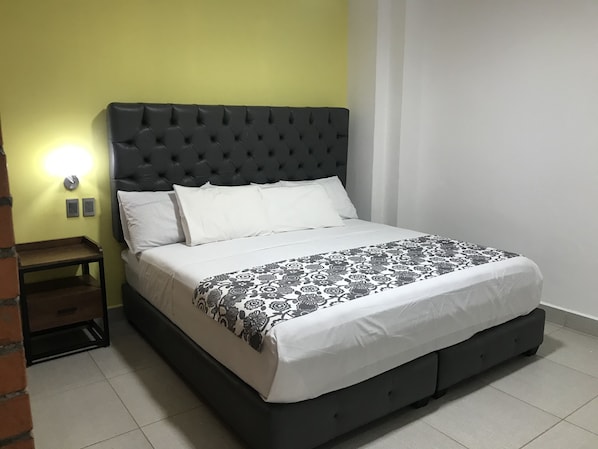 A bed with a tufted headboard, white bedding, and a patterned throw.