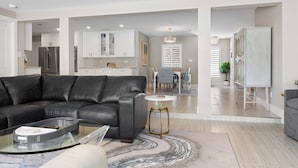 Un salon moderne avec un canapé en cuir, une table basse en verre et un coin repas à l’arrière-plan.