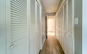 Stylish hallway with louvered closets and a door at the end.