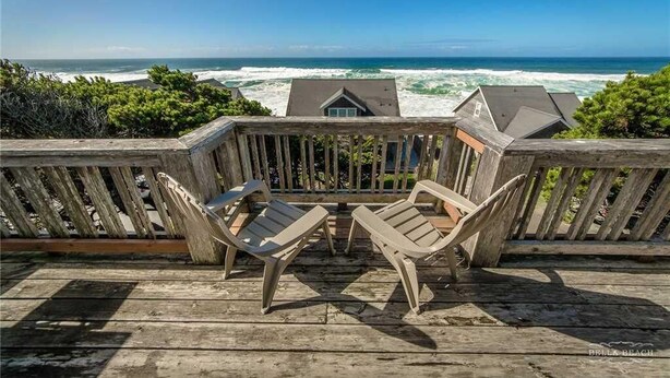 A wooden deck with two chairs facing a view of the ocean. - Cloud Nine (Depoe Bay)