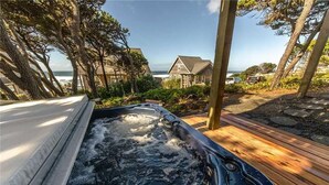 A hot tub with a wooden deck and a view of houses and the ocean. - Cloud Nine (Depoe Bay)